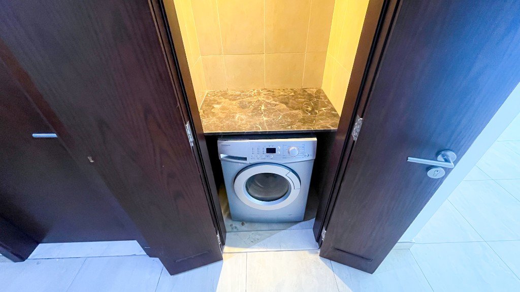 Laundry cupboard with a washing machine in the Azizi Freesia apartment