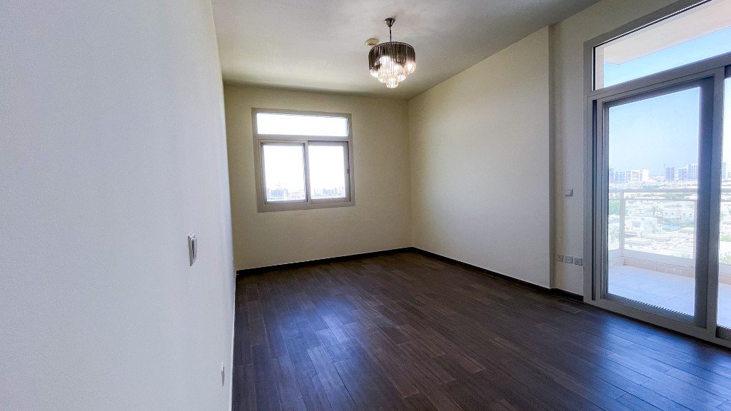 Bedroom with dark wood flooring and a balcony in Azizi Freesia