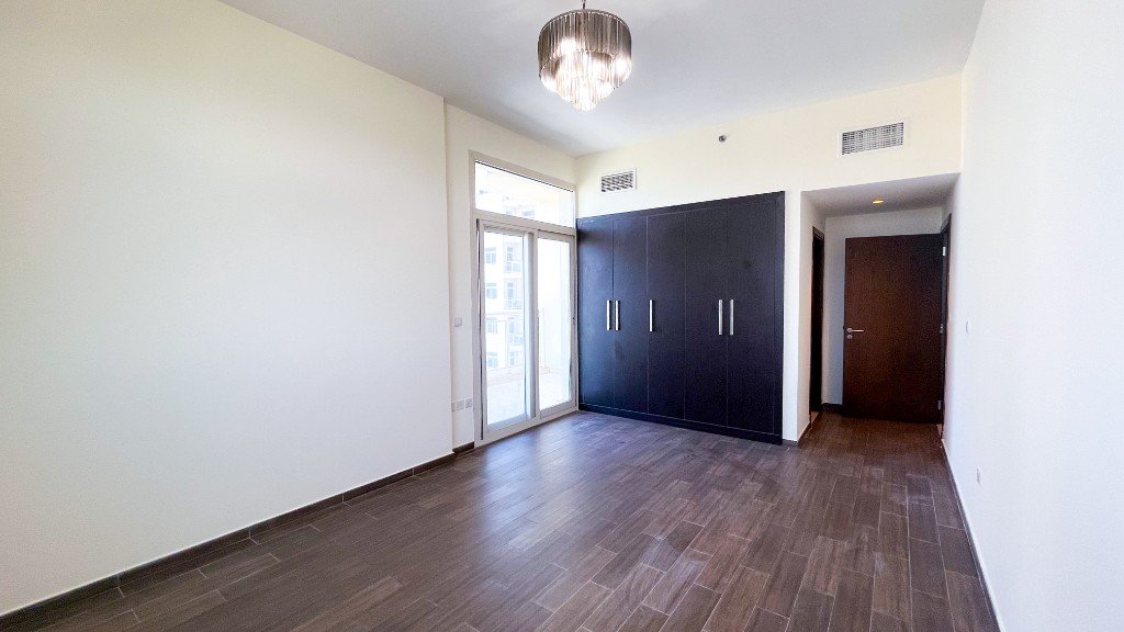 Bedroom with built-in wardrobes and a balcony door in Azizi Freesia