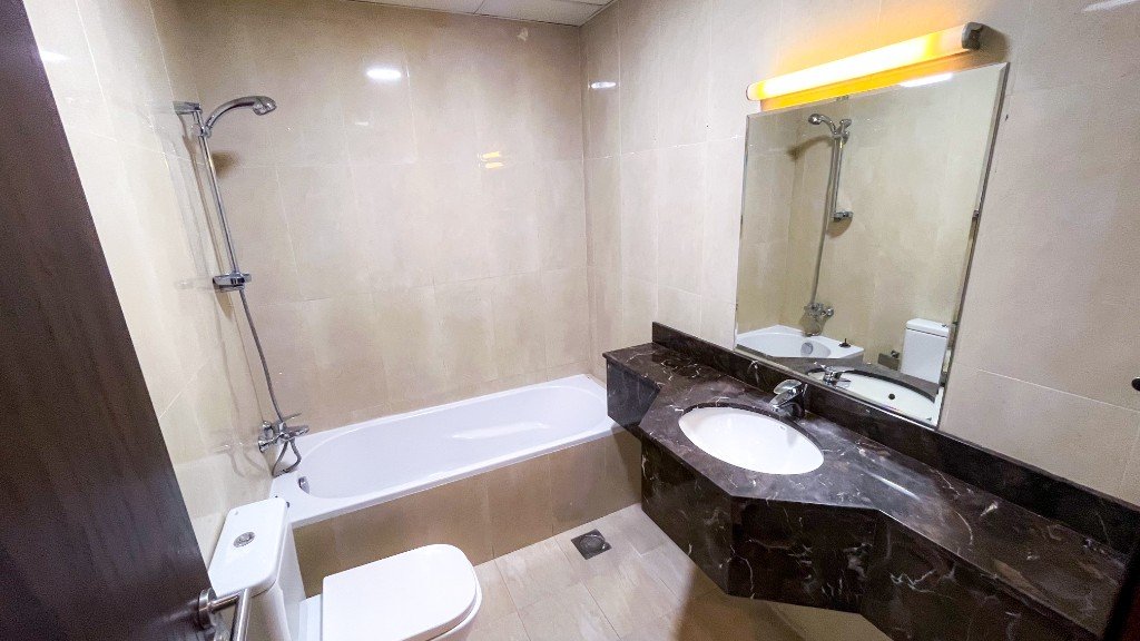 Bathroom with a bathtub and dark marble vanity in Azizi Freesia